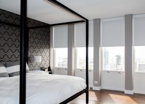 white bedroom brown wallpaper accent wall, white floor to ceiling roller shades in Chicago IL