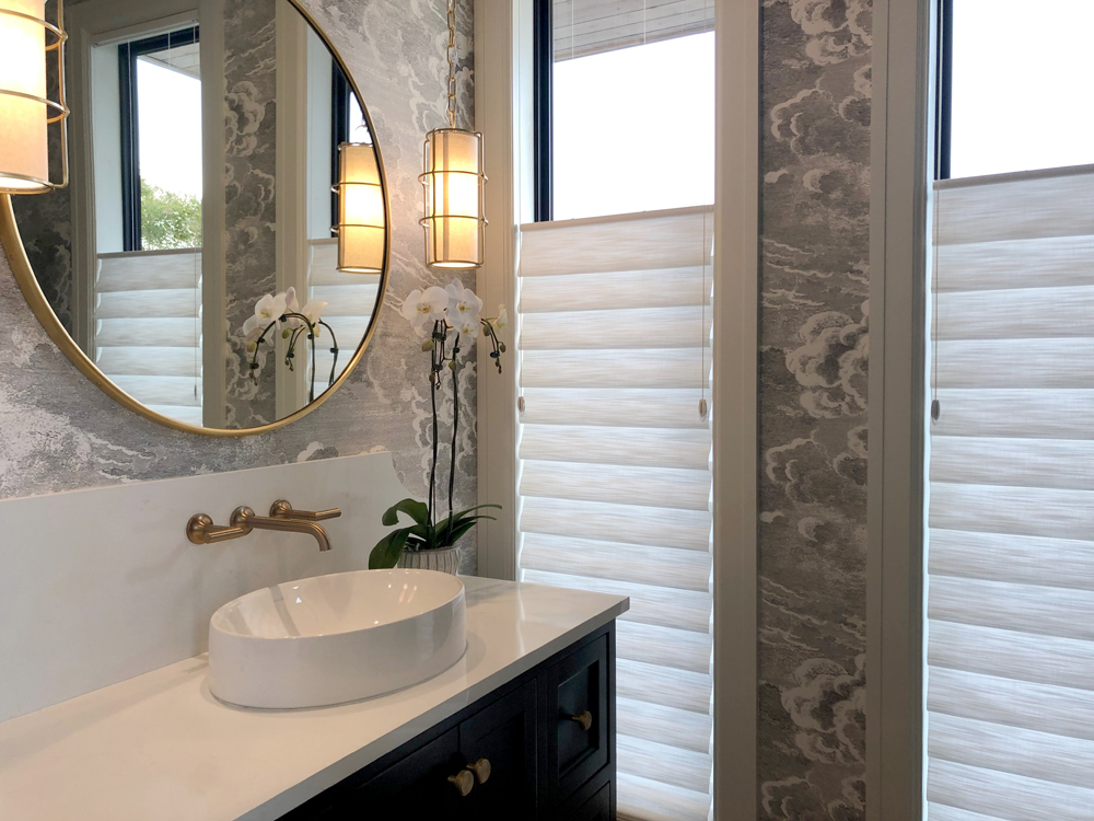 bathroom with gray wallpaper circle mirror and top down roman shades on narrow windows in Chicago IL