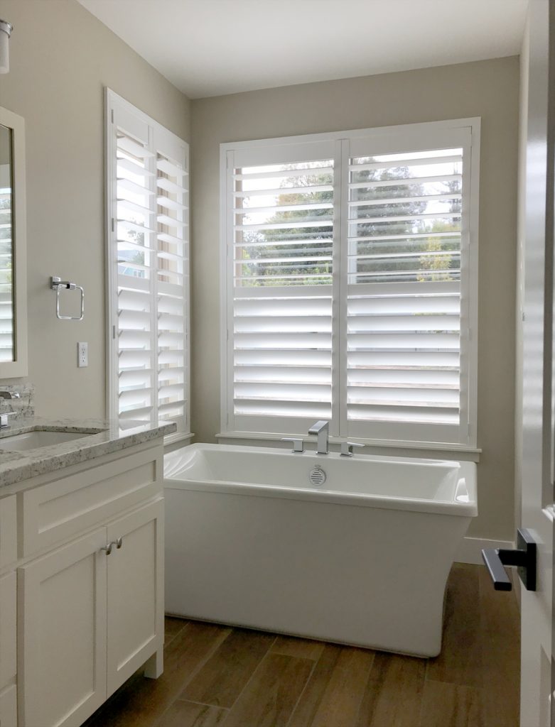 bathroom with corner tub and white shutters on windows in Chicago IL