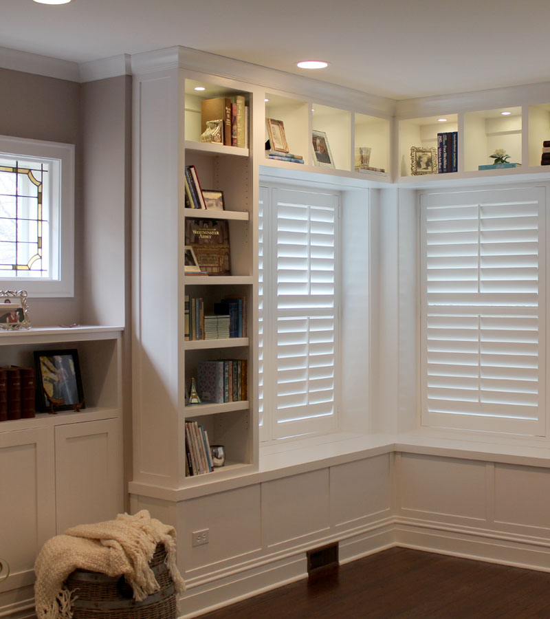 corner of living room with built-in shelves and windows with interior shutters in Hinsdale IL