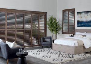 wall of dark plantation shutters for glass doors in bedroom Beaverton OR