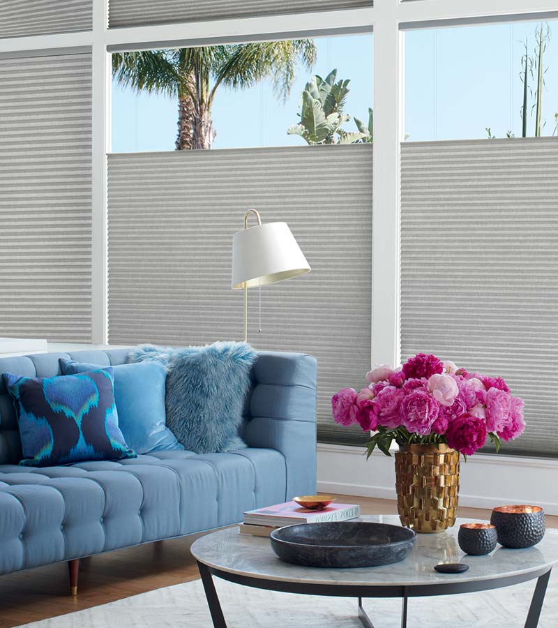 cellular blinds lowering from the top in living room with blue sofa in Portland OR