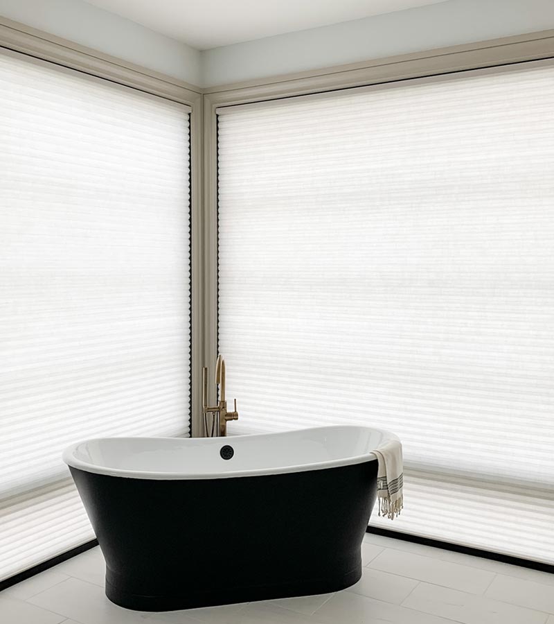 large windows in master bathroom covered with honeycomb shades