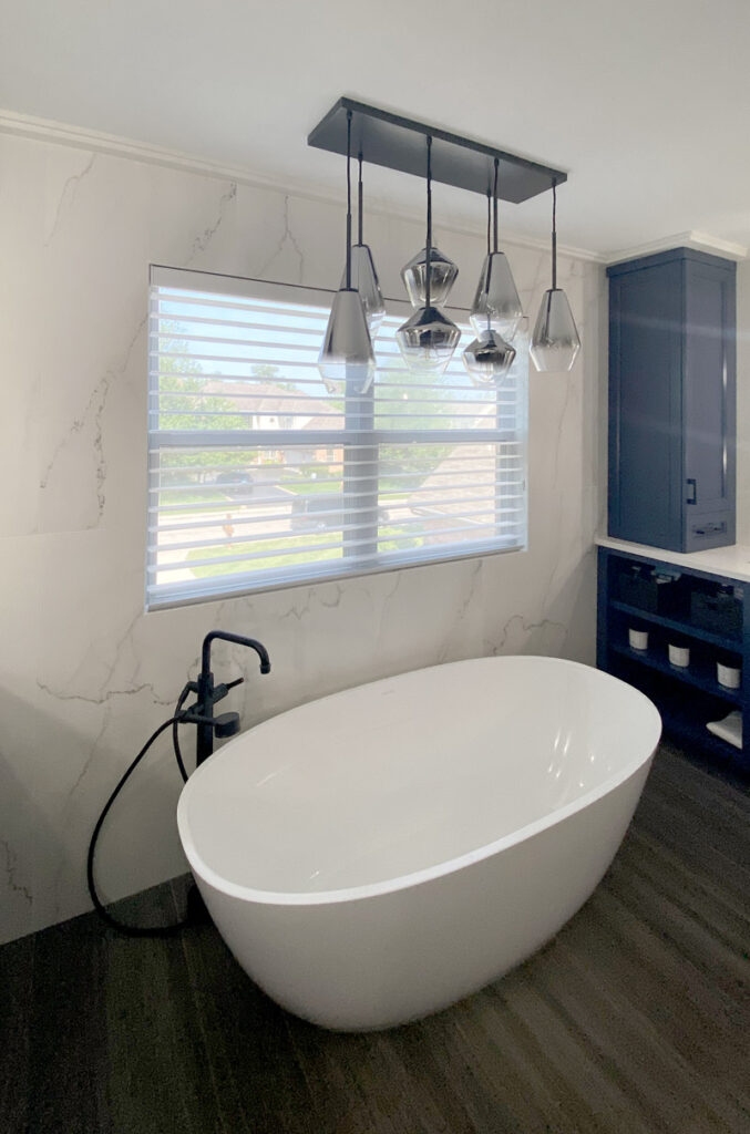 master bath with marble wall and silhouette shades over standing tub