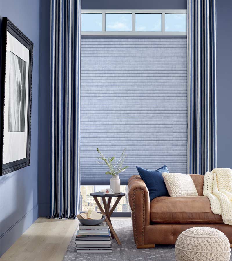 blue living room with tall window, open transom, blue honeycomb shade and side draperies
