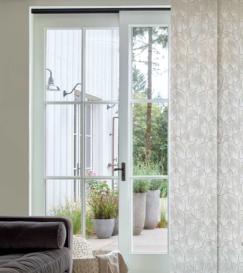 exterior french door partially covered by white patterned vertical window shade panel