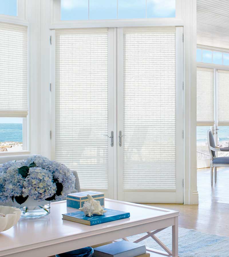 coastal inspired living room exterior french doors and cream woven wood shadings