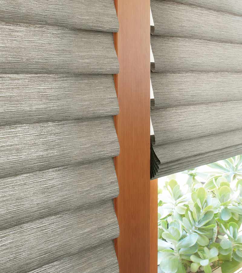 soft fabric roman shades in organic materials on patio door overlooking plants