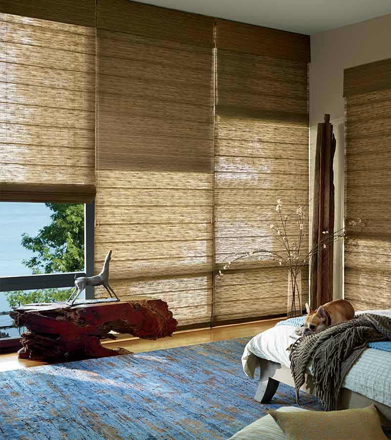 master bedroom with large floor to ceiling window treatments in caramel shades in alustra organic materials