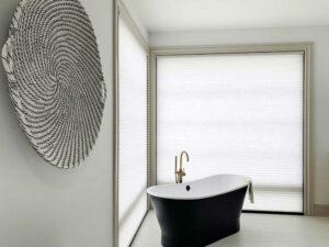 large master bathroom windows covered with honeycomb shades and black standing tub in the corner