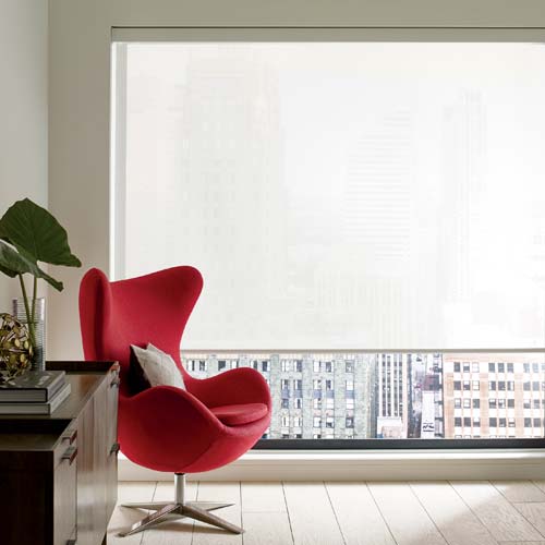 white screen shades on large windows with red modern chair