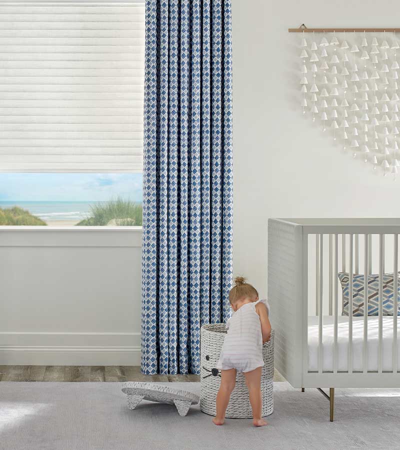 little girl playing in nursery with blue patterned drapery overlooking lake in West Hollywood, CA