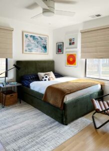 boy's bedroom with green fabric bed and roman shades on black trim windows