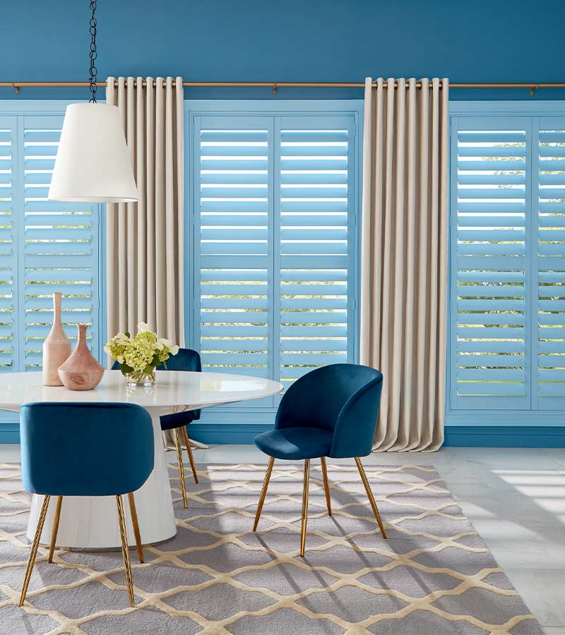 blue wooden shutter painted a pale blue in modern dining room space with drapery