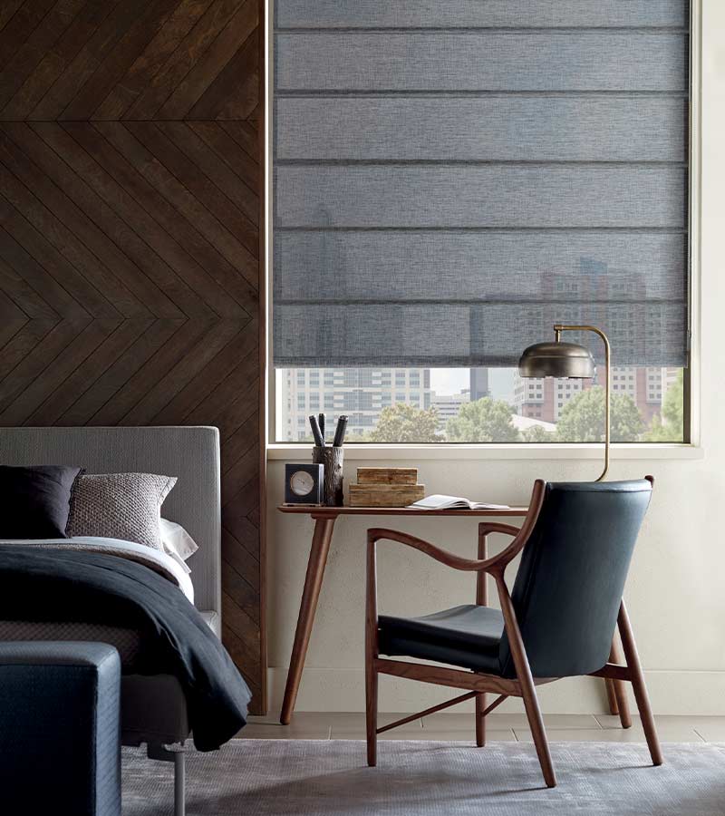 guest bedroom with modern desk, chair, and lamp with gray window treatments