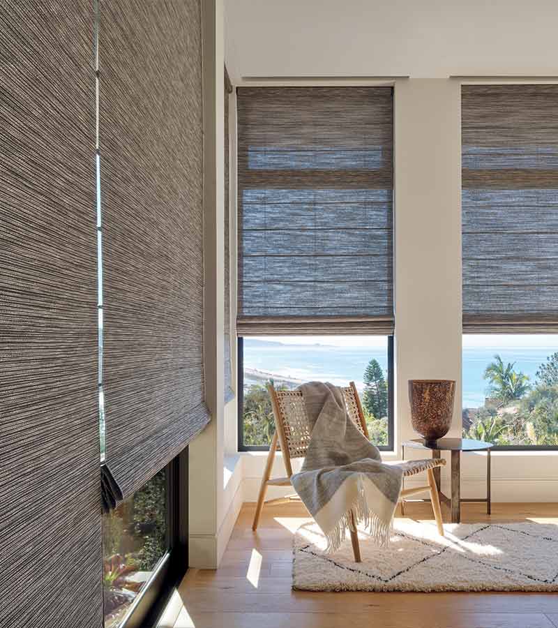 Woven shades on large windows in vacation home overlooking the outdoors