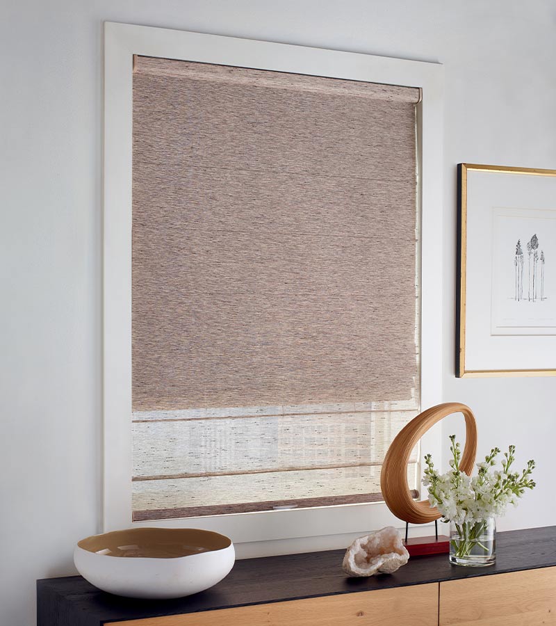 Dual shades on living room window over a black wood credenza