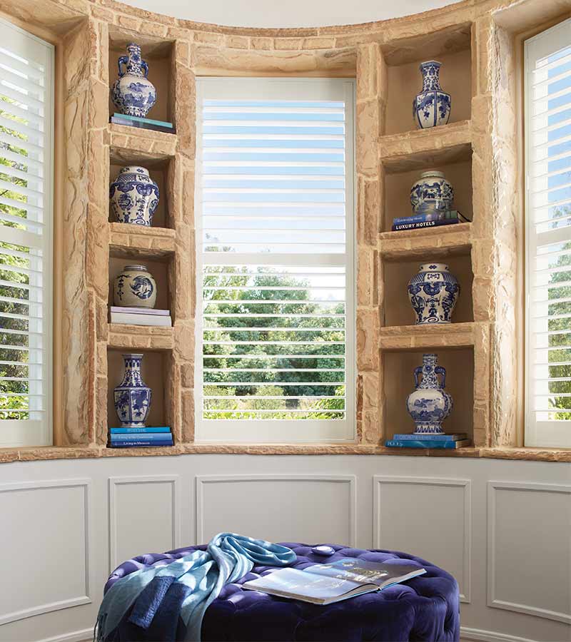 white plantation shutters on bay window with stone built ins