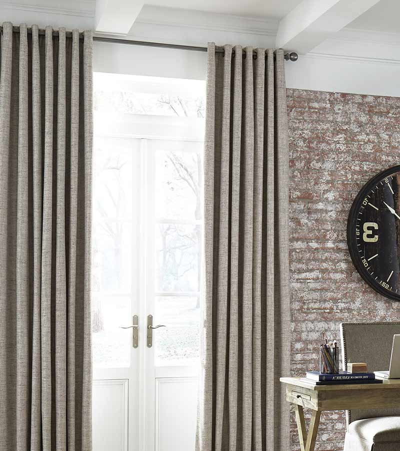 brown curtains next to exposed brick wall in contemporary home office