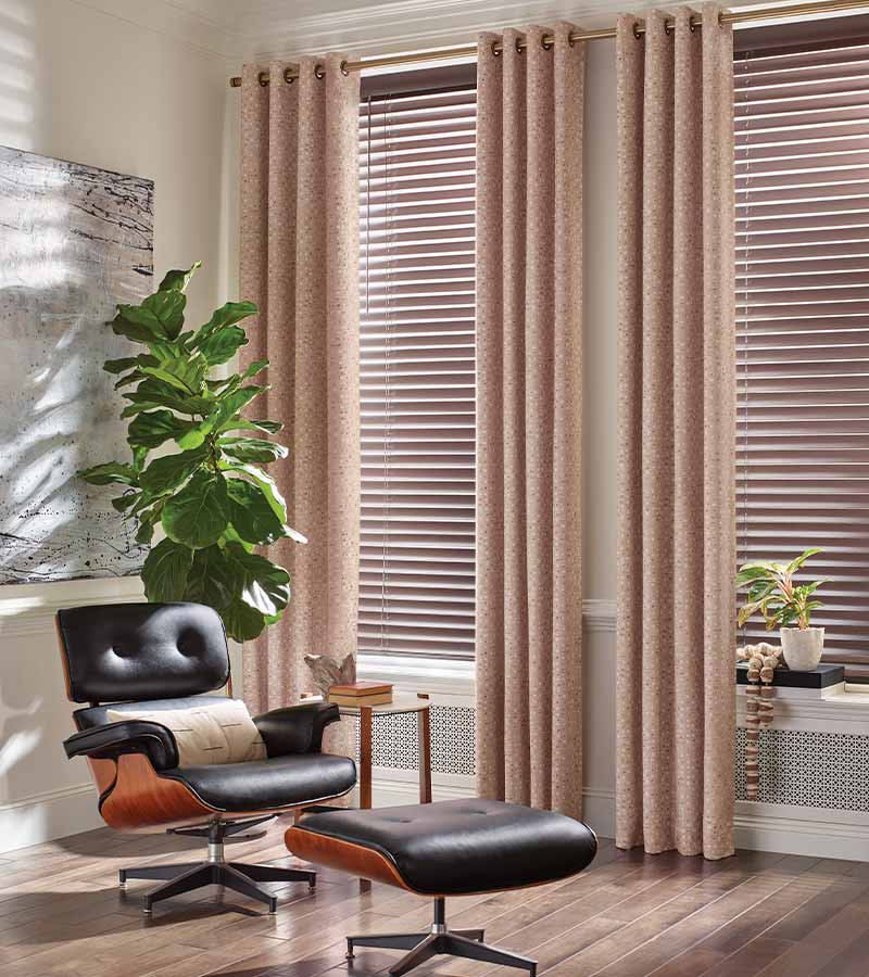 mcm chair in corner of living room pink floor to ceiling drapery and hybrid blinds