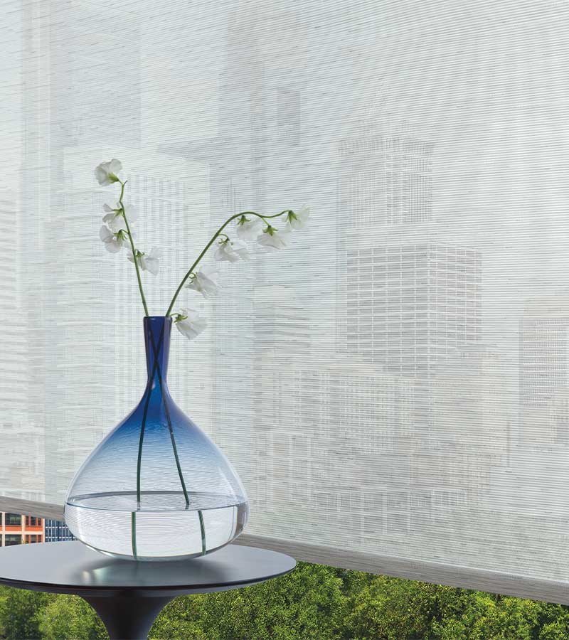 blown glass vase with blue top in front of gray screen shades