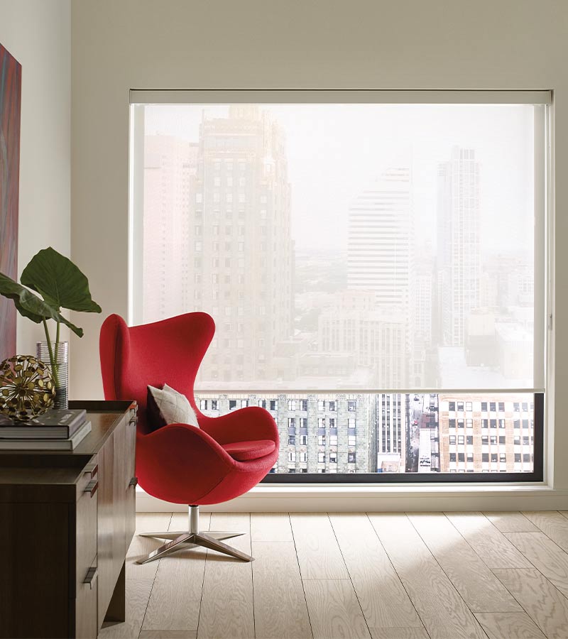 modern red barrel chair in front of large square window with shade half way down