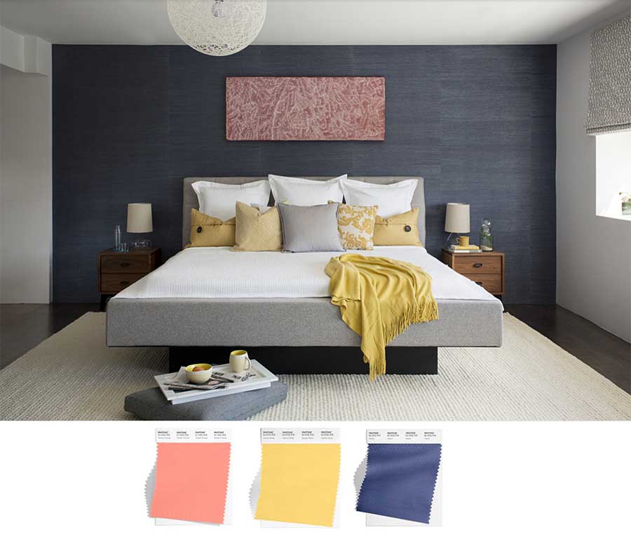 large bedroom with deep blue grasscloth wallpaper and coral colored art