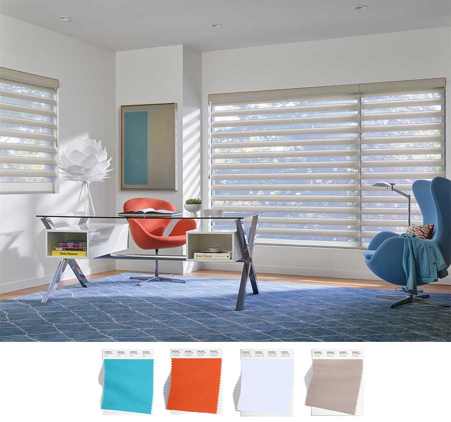 beige pirouette shades cover the large windows of this home office decorated with blues and accented with an orange chair