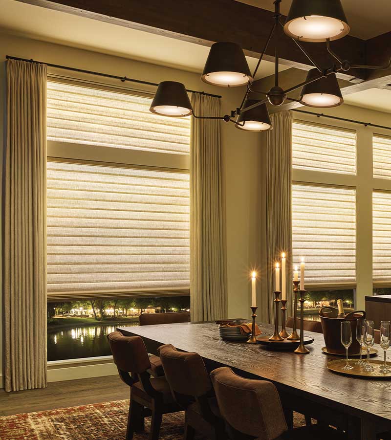 a cozy dining room set for dinner and side draperies layered over aura shades