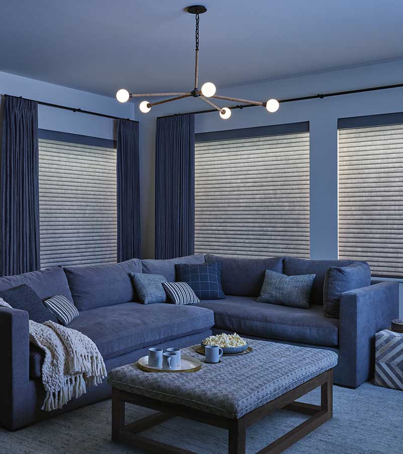 in-home media room with drapery side panels and a light illuminating window shade