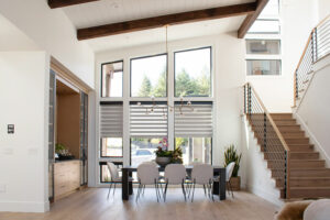 Two story dining room with angled windows and wood and iron staircase