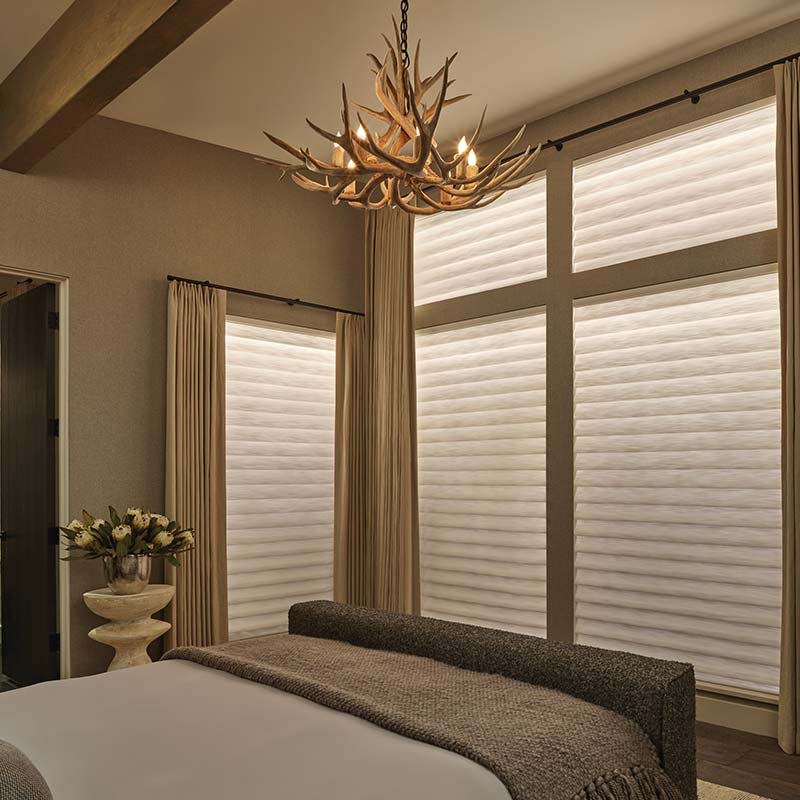 bedroom with large window coverings glowing with interior backlighting