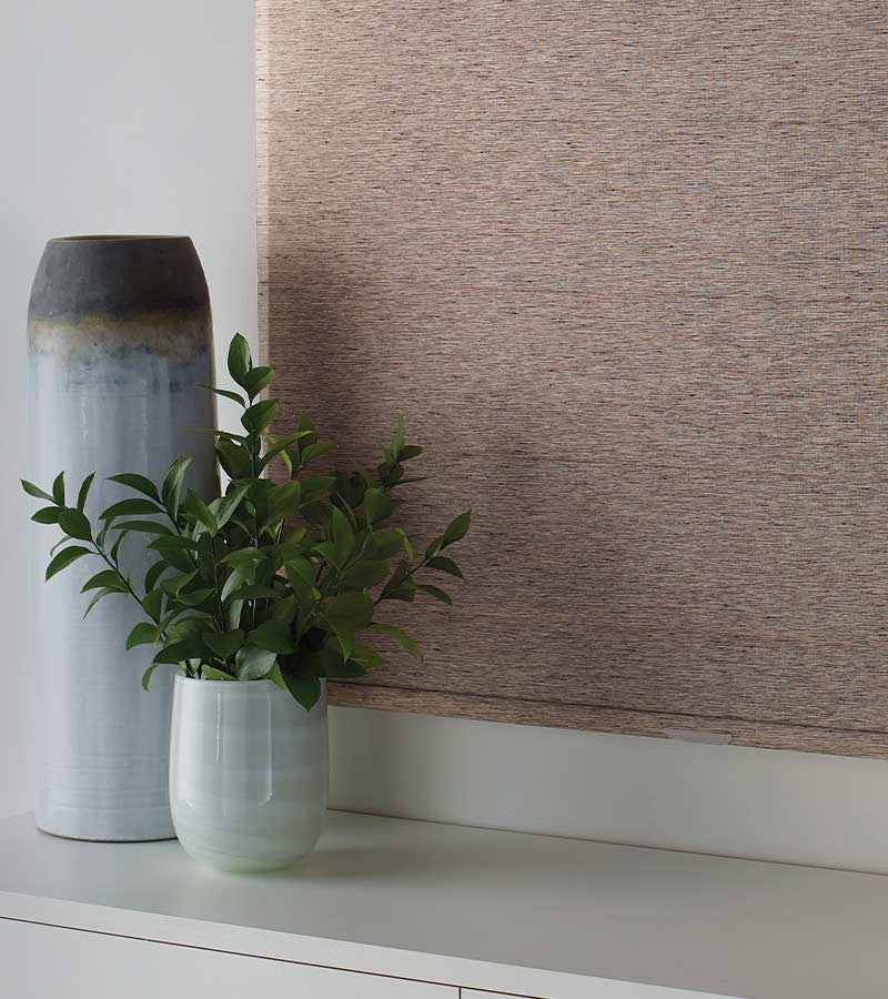 roller shade in textured fabric from alustra next to house plant and vase