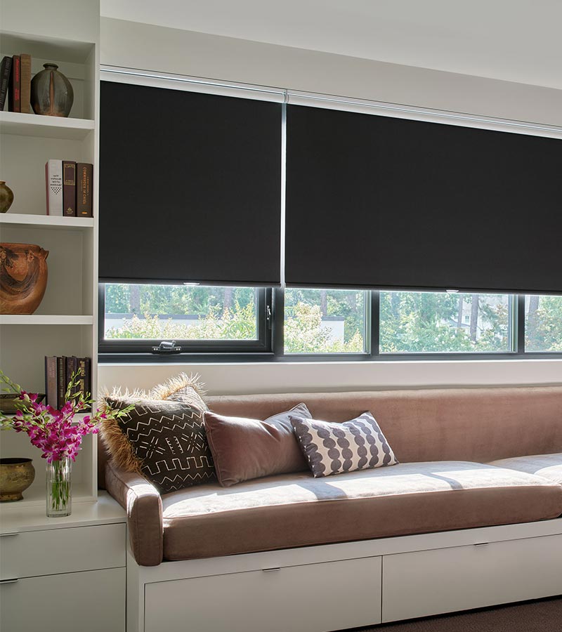 black shades on window above reading bench flanked by white cabinets with home decor