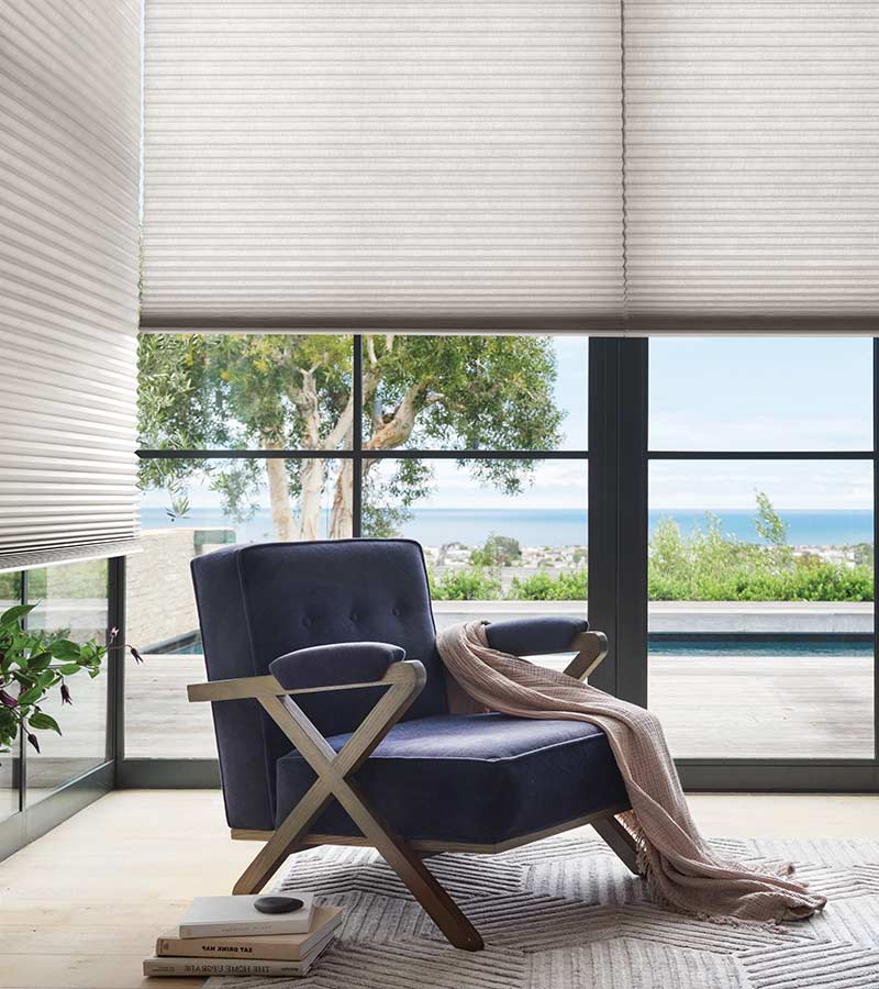 window seat with white honeycomb window shades in bedroom